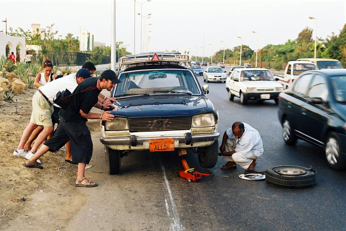 A driver checking their credit card benefits booklet with red circle highlighting 'assistance service limit' text