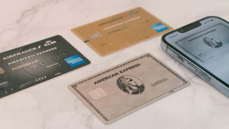 Flat-lay of credit card next to car keys and emergency roadside kit on asphalt